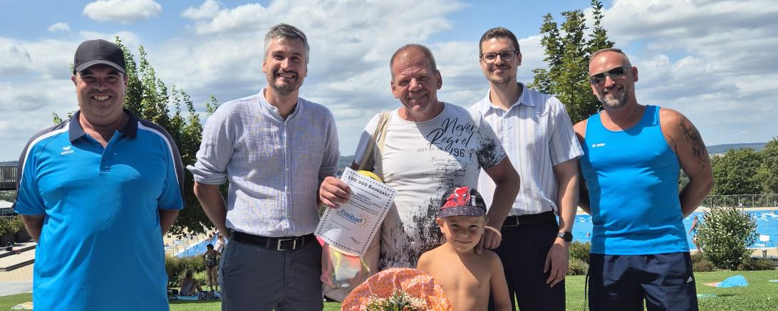 Bürgermeister Jonathan Schädle (2.v.l.) begrüßt Jürgen Miehle (m.) und seinen Sohn Lennox im Donauwörther Freibad. 