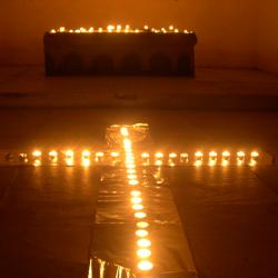 Kerzen bilden ein Kreuz auf dem Boden vor einem Altar