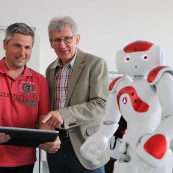 Zwei Männer mit Tablet und Roboter