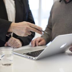 Zwei Männer an einem Stehtisch mit Laptop