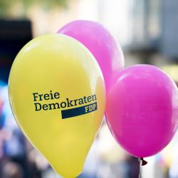 Drei Luftballons, zwei in magenta, einer gelb mit Aufdruck "Freie Demokraten FDP"