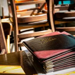 Das Bild zeigt ein leeres Restaurant und Speißekarten auf einem Tisch liegen