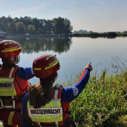 Das Bild zeigt zwei Wasserretter, die die örtlichen Gegebenheiten erkunden und achten auf mögliche Gefahrenquellen.