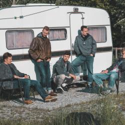 Fünf junge Männer vor Wohnanhänger