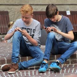 Das Bild zeigt zwei Jugendliche an ihren Handys. 
