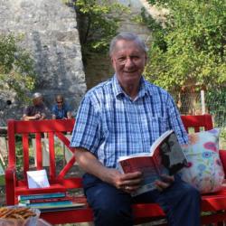 Auf dem Bild sieht man Manfred Hahn mit einem Buch in der Hand. Er wird am 31. Oktober eine Vorlesung im B+ Zentrum Blossenau machen