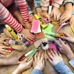 Kinderhände greifen sich Bastelmaterialien
