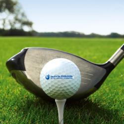 Zu sehen ist ein Golfball mit der Aufgschrift "Deutsche Krebshilfe" vor einem Golfschläger. 