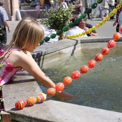 Auf dem Bild ist ein Kind an dem geschmückten Osterbrunnen zu sehen.