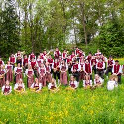 Menschen in Roten Trachten auf einer Wiese 